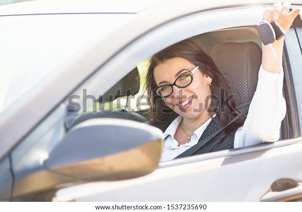 Plus size model
sitting at the wheel of own car and shows the keys. Buying or
renting a car in the
showroom