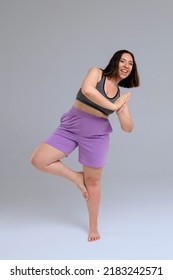 Plus Size Model In Sport Outfit Doing Yoga On Light Blue Background Isolated