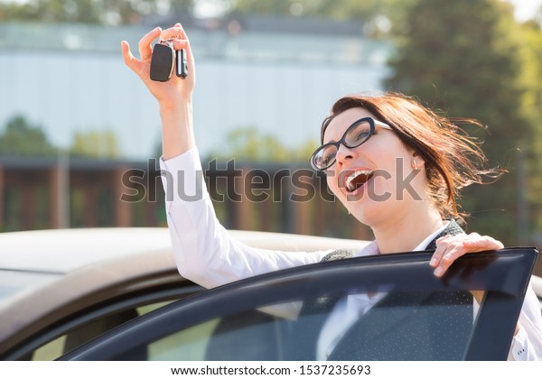 Plus size model standing\
near her own car and shows the keys. Buying or renting a car in the\
showroom