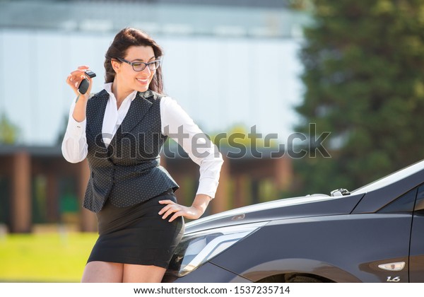 Plus size model standing\
near her own car and shows the keys. Buying or renting a car in the\
showroom