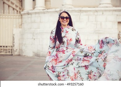 Plus Size Model Wearing Floral Maxi Dress Posing On The City Street. Young And Fashionable Overweight Woman Walking Around Town.