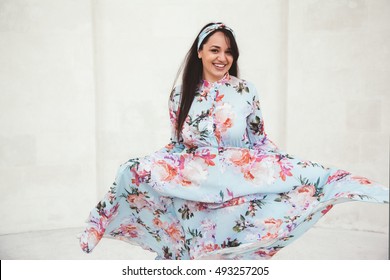 Plus Size Model Wearing Floral Maxi Dress Posing On The City Street. Young And Fashionable Overweight Woman Walking Around Town.