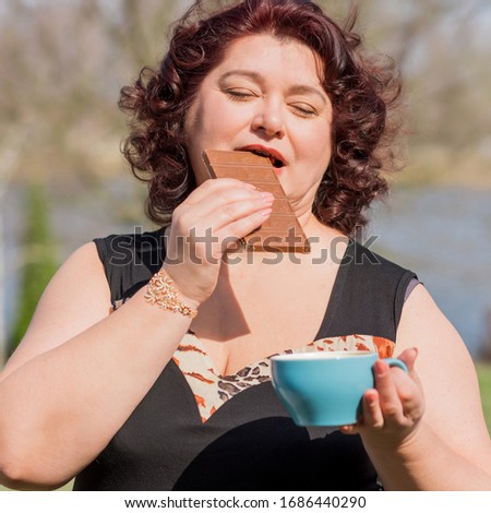 Plus size nice mature woman with chocolate and coffee. Diet and food concept