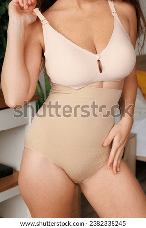 Plus size pretty model in correcting figure (body) stretch beige shorts.
Beautiful lady with big breasts and small waist wear underwear to correct her figure. Woman with long hair in bedroo in panties
