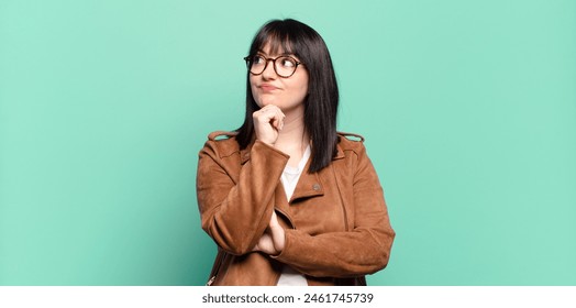 plus size pretty woman feeling thoughtful, wondering or imagining ideas, daydreaming and looking up to copy space - Powered by Shutterstock