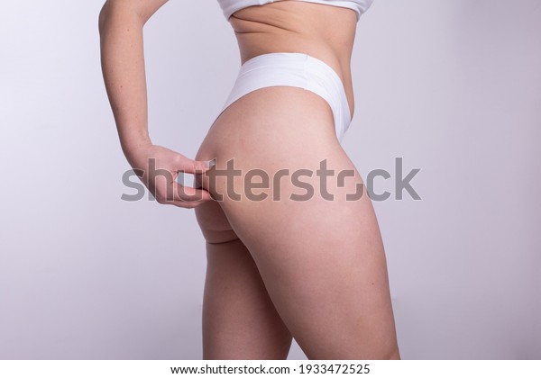 Plus Size Real Body Woman Model with in underwear\
cheking fat on legs and waist, imperfect nonideal body positivity\
concept