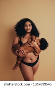 Plus size woman breastfeeding her infant. Mother with baby in hands standing and breastfeeding.