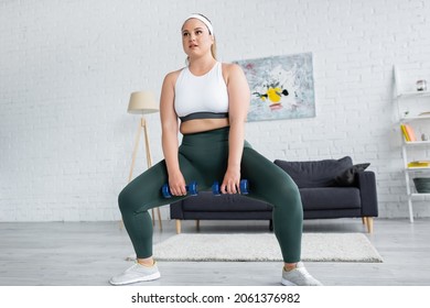 Plus Size Woman Doing Squat While Training With Dumbbells At Home