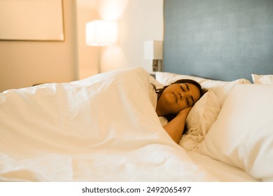 Plus size woman is enjoying a relaxing vacation by sleeping soundly in a comfortable hotel room bed - Powered by Shutterstock