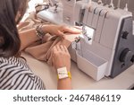 A plus size woman fashion designer uses an overlock sewing machine in her studio. A seamstress sews clothes in her sewing workshop.