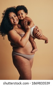 Plus Size Woman Holding Her Baby Up. Strong Body Positive Woman Postpartum. Real Body Of A Healthy Mother.