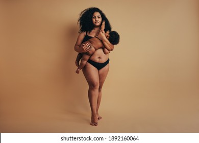 Plus size woman holding her baby and breastfeeding. Strong body positive woman postpartum.