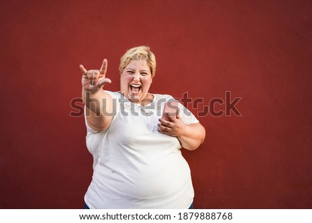 Plus size woman listening rock music on mobile phone - Focus on face