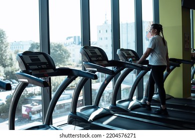 Plus size woman run on modern treadmill at fitness gym and look out window at city life. Middle aged lady do cardio workout on exercise machine. Weight loss, keep in shape, sport lifestyle. - Powered by Shutterstock