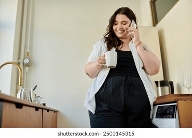 A plus size woman smiles while holding a mug and chatting on the phone. - Powered by Shutterstock