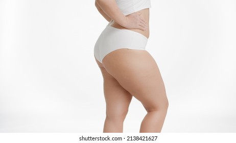Plus size woman in white underwear puts her hand on her waistline on white background | Unwanted leg hair removal concept