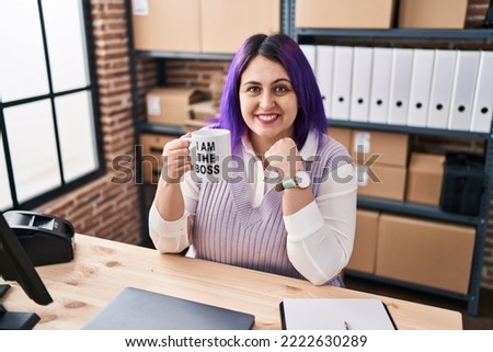 Plus size woman wit purple hair working at small business ecommerce holding i am the boss cup looking positive and happy standing and smiling with a confident smile showing teeth 