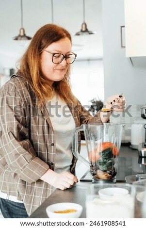 Plus size young woman adding bee pollen during making smoothie on the kitchen. Superfood supplement. Healthy detox vegan diet. Healthy dieting eating, weight loss program. Selective focus