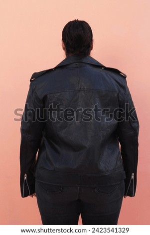plus sized female model posing in black leather jacket and black jeans with glasses and high heels 