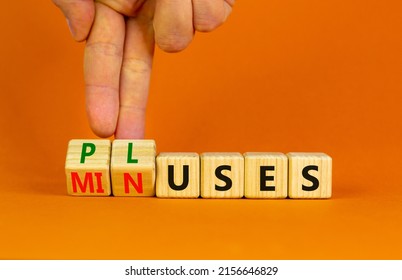 Pluses and minuses symbol. Businessman turns wooden cubes and changes the word 'minuses' to 'pluses'. Beautiful orange table, orange background. Business, pluses and minuses concept, copy space.