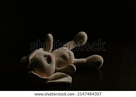 Plush bunny laying down alone at night. Lonely concept, international missing children's day.