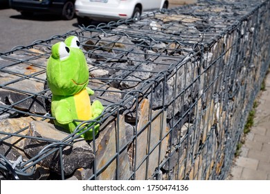 Plush Toy - A Frog, On A Stone Gabion Wall In The City