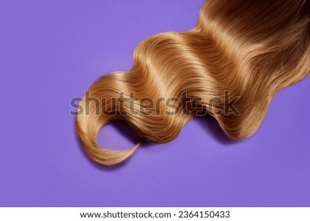 Ply of shiny, healthy, glowing blonde hair with wavy styling on purple background. Professional hair treatment. Concept of hair care, organic products, natural beauty, cosmetics. Ad. Poster.