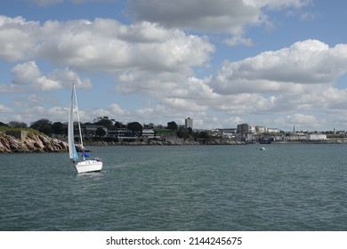 Plymouth England April 2022. Lone yacht in sail in Plymouth Sound with Plymouth Hoe in the background