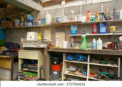 Plymouth England. Interior of block built domestic DIY shed. Open cupboards with rope, tools, garden tool boxes, plant pots, shelves with sprays, used paint tins, wall tiles in boxes.  