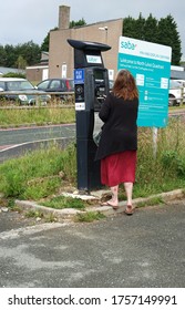 Plymouth England. June 2020. Derriford University Hospital. Car Park Showing Lady Using Parking Machine For Hospital Parking. Signage On Notice Board With Tariff, And Payment Machine. 