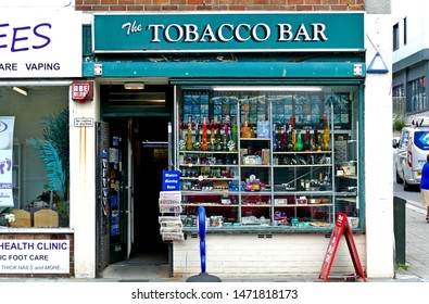 Plymouth England. Tobacco Bar Shop Selling All Types Of Tobacco Products From Cigarettes To Pipes. Green Sign Large Window Display, Open Door.  Being Overtaken Pushed Out By Vaping Stores.