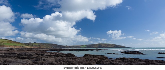 Plymouth UK. 3/7/19:  Wembury Bay And The Yealm Estuary On A Sunny Day With A Rocky Shore In The Foreground.