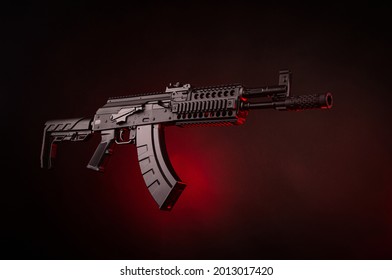 A pneumatic copy of a Russian machine gun. Modern airsoft weapons. Dark background with red illumination.