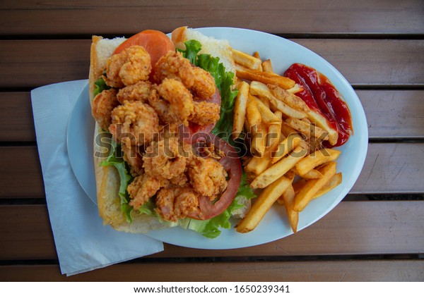 A Po Boy shrimp sandwich with\
French Fries and ketchup on the side found in Key West,\
Florida