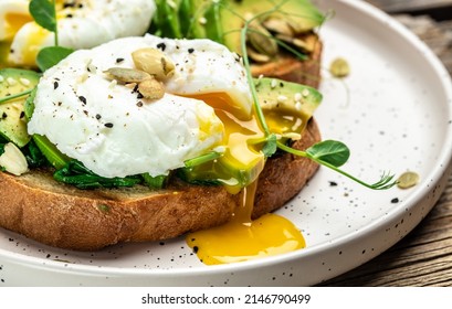 Poached egg on on bread with spinach, avocado and pumpkin seeds, Healthy food, keto diet, diet lunch concept. Top view.