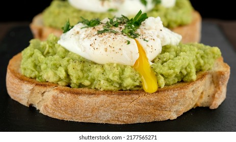 Poached Egg With Runny Egg Yolk Over Bread Toast With Mashed Avocado Spread