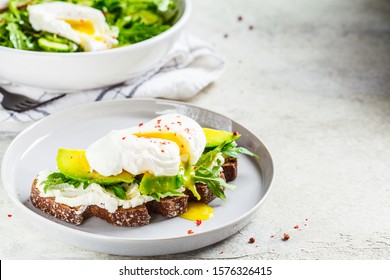 Poached egg toast with avocado, cream cheese and rye bread on a gray plate. Healthy food concept. - Powered by Shutterstock