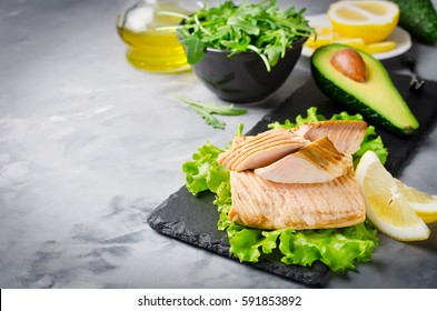 Poached Salmon, Arugula, Lemon, Oil, Avocado. Gray Concrete Background