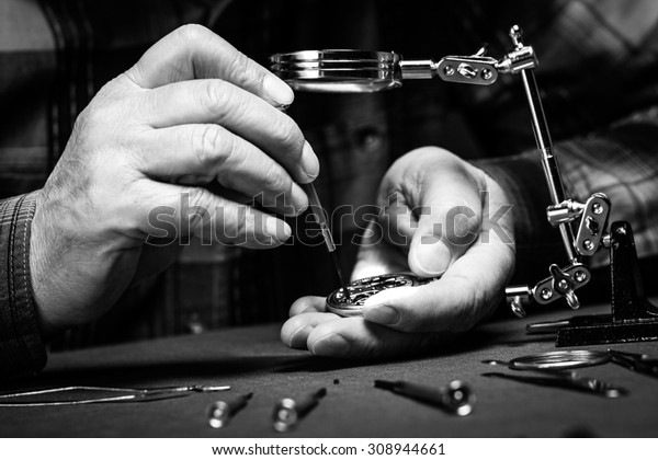 Pocket watch being repaired by senior watch maker,\
close-up. Black and\
white.