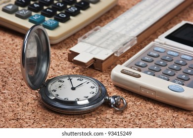 Pocket Watch,  Calculator  And Slide Rule On A Cork Board