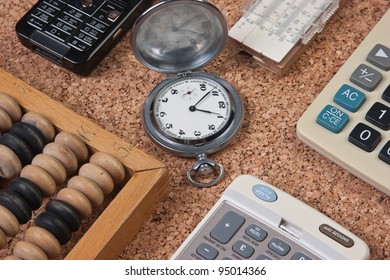 Pocket Watch, A Calculator, A Wooden Abacus And Slide Rule On A Cork Board