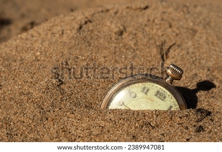 Pocket watch lying in the sand on the beach.Sand and time on the clock. Lost time.
