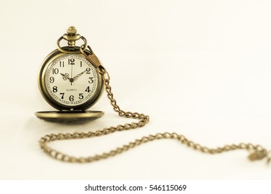 Pocket watch on plain background in sepia tone