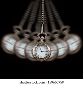 Pocket watch silver swinging on a chain black background to hypnotise