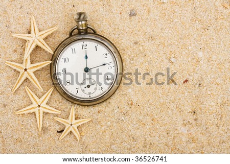A pocket watch with starfish in the sand on the beach, summer vacation