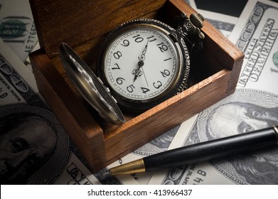 Pocket watch in wood box with pen and money.