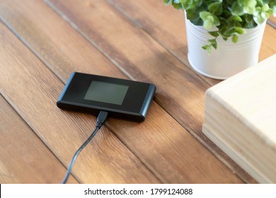 Pocket wifi with battery charger on brown wood table
