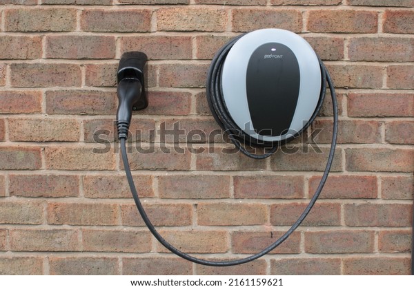 Pod Point domestic home electric vehicle
charging point mounted on a brick wall with copy space. Lancashire,
UK, 27-05-2022