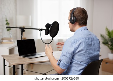 Podcast And Blogging Concept - Back View Of Male Host Or Blogger Recording Audio Podcast In Home Studio