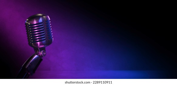 Podcast, comedy club or jazz club banner with vintage microphone nad copy space. Old mic in the dark with blue and pink lighting and wide background.